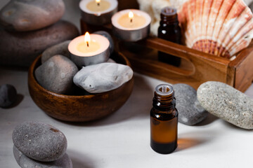 Spa composition with essential oil, stones, shell, soft towel, candle. Aromatherapy and relax, atmosphere of serenity and relaxation. Close up, macro view. White wooden background, tonned