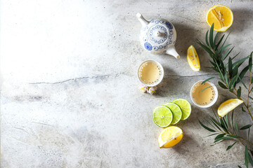 Fototapeta na wymiar Tea set, lemon, mint and flowers on a light concrete background. View from above. Tea party concept.