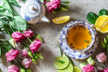 Tea set, lemon, mint and flowers on a light concrete background. View from above. Tea party concept.