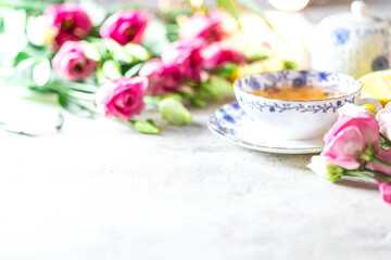 Porcelain cup of herbal green tea, lemon, mint and flowers on light grey background.