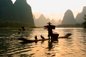 Silhouette of cormorant fisherman on the Li River (Lijiang) with karst peaks in the background at...