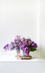 Bouquet of the beautiful spring purple lilac flowers on light background. Common Syringa plant. Floral composition on wooden slice in minimalist light interior