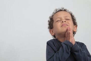 boy praying to God with hands together and closed eyes on white background 