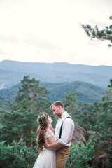 Wedding. Bride and groom holding hands standing on the hillside and looking at the sunset