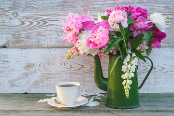 Romantic greeting card with cup of coffee and bouquet of peonies in vintage green coffee pot on...