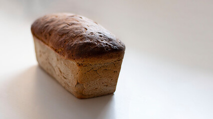 Freshly baked crusty loaf of homemade premium rye and wheat flour bread on white table. Contains gluten, Vegetarian food. Baking at home using sour dough. Horizontal banner with copy space