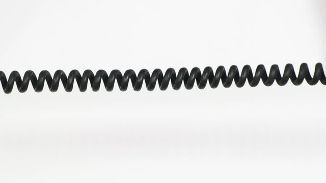 Close up of rotary phone coiled cord on white