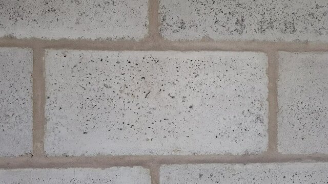 Wall of gray cinder block with sloppy seams. Front view.