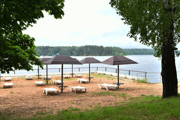 sandy beach with umbrellas and sunbeds on the banks of the river