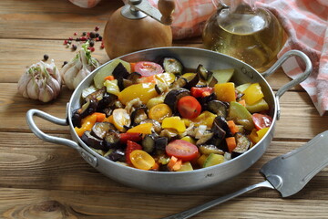 Vegetable stew with eggplant and zucchini on a wooden background
