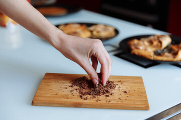 The hand of pastry chef with grated chocolate. Going to sprinkle the cake