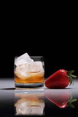 Whiskey on the rocks and strawberries on a dark background