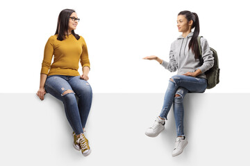 Two young female friends sitting on a panel and talking