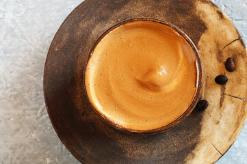 Dalgon coffee in a ceramic Cup on a plate with coffee beans. Indian origin, whipped instant coffee with sugar and water, based on milk.Close-up, top view, macro..