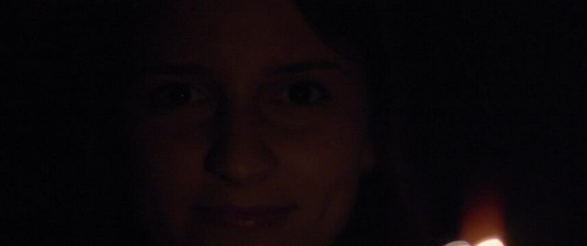 Close up portrait of a woman smiling, with sparkles in front of her in beautiful bokeh. Holiday, celebration concept. Slow motion, shallow DOF, BMPCC 4K