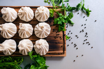 Khinkali dumplings pastry dish on a wooden board, decorated with parsley and peas of black pepper. top view