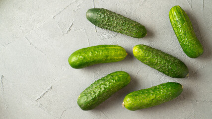 Fresh green ripe cucumbers on gray concrete background. Scattered cucumbers. Gherkins on the table close-up.