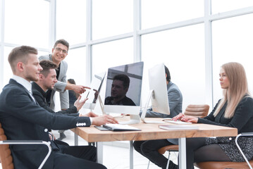 side view. confident young businessman sitting at the office Desk.