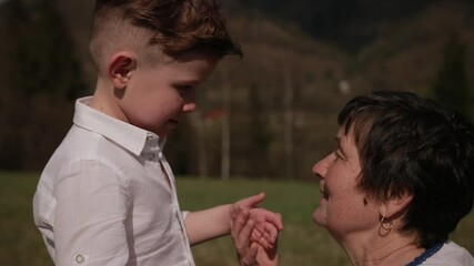 Grandson cries, tears flow from eyes, screams to his grandmother, relations between generations, conflict, feelings. On a large clearing, bright sunny day