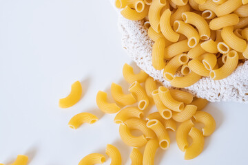 Raw dry uncooked Elbow Macaroni pasta spaghetti on white background. Good for basil tomato pesto...