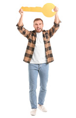 Happy young man with big paper key on white background