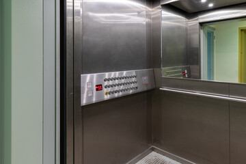 Elevator, with wide doors, adapted for wheelchair users, with a low-mounted control panel with horizontal rows of buttons. Accessible environment for the disabled