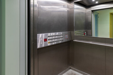 Elevator, with wide doors, adapted for wheelchair users, with a low-mounted control panel with horizontal rows of buttons. Accessible environment for the disabled © hodim