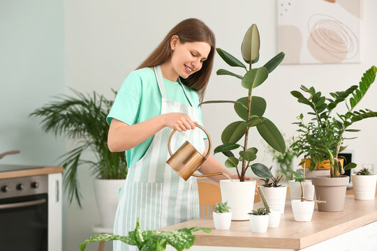 Young Woman Watering Plants At Home