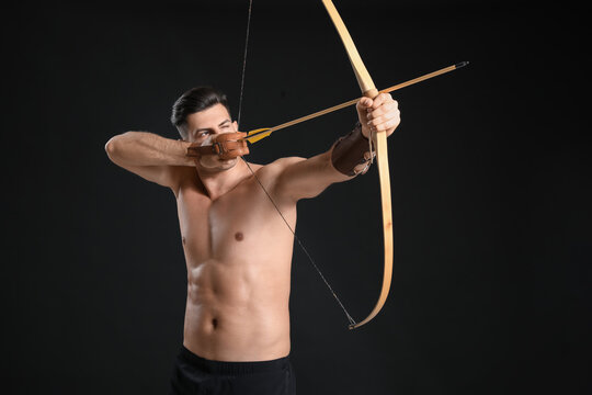 Handsome man with crossbow on dark background
