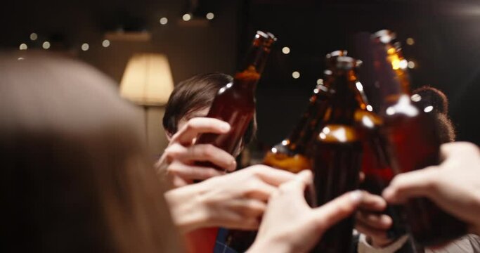 Group of happy multiethnic friends having fun together, drinking bottled beer in a bar or at home, celebrating, happily smiling - friendship, togetherness concept 4k footage