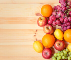 Naklejka na ściany i meble Fresh ripe apples, lemons, oranges and grape as border on wooden background.