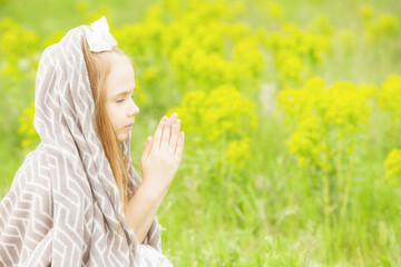 Blonde girl prays to god on green glade