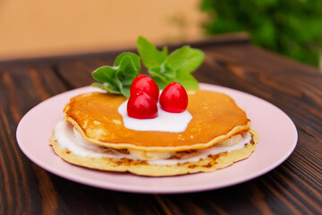 pancakes with yogurt lie on a plate  on a wooden background