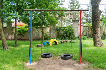 A children's playground made of old tires. Two children's swings made of a car wheel.