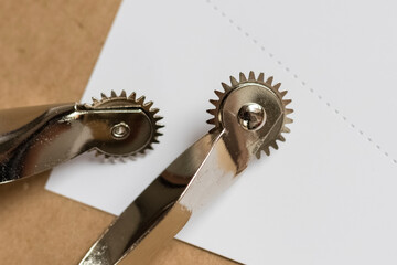 Sewing tool for leather sewing. Perforated white paper on kraft paper background. Close-up