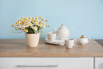 Vase with beautiful chamomiles on table in kitchen
