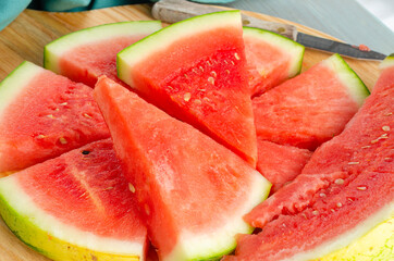 Slices of watermelon on a wood cutting board and wooden background