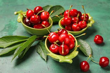 Bowls with sweet cherry on color background