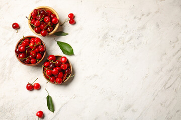 Bowls with sweet cherry on light background