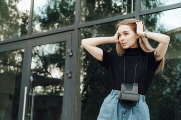 A beautiful stylish blonde walks with a film camera нipster casual 
against the background of a...
