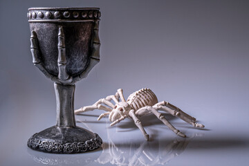 Tarantula skeleton inspects a goblet of poison.