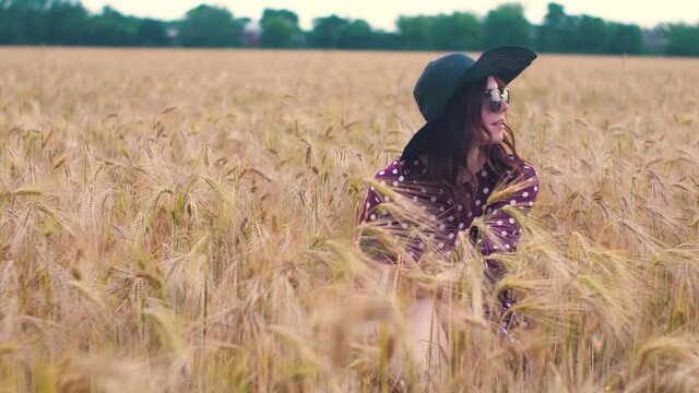Beautiful young hippie woman in the wheat field at sunset uses a smartphone