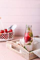 Bottle of fresh strawberry lemonade on table