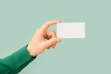 Female hand with blank business card on color background