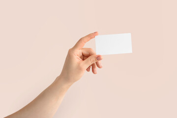Female hand with blank business card on light background