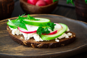 Bruschetta sandwiche with cucumbers, radishes and persil microgreen on wooden board