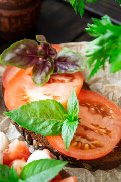 Traditional italian bruschetta appetizer or snack with tomato slace and basil, antipasto.