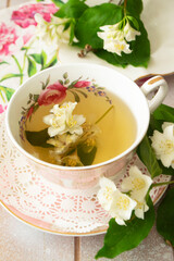 Vintage cup of hot green tea with jasmine flavor and fresh jasmine flowers.