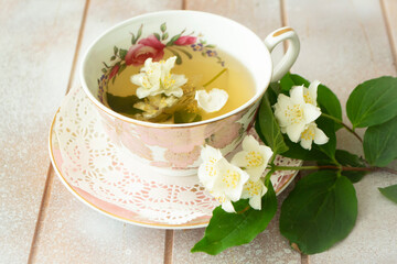 A cup of green tea with jasmine flowers. Fresh jasmine branches. Jasmine tea. Vintage classic cup