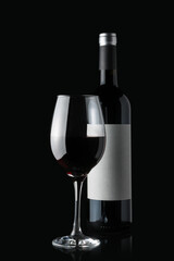 Glass of red wine next to a bottle isolated on black background